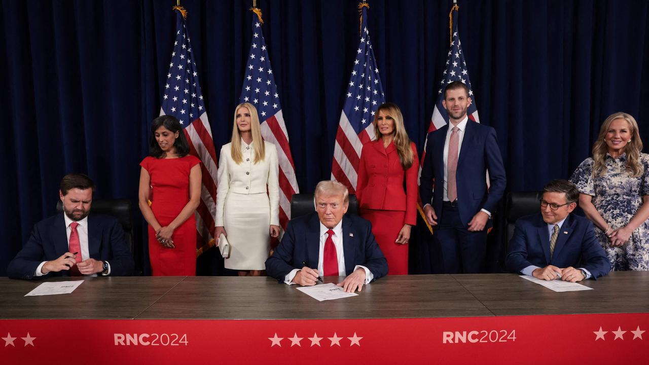 Donald Trump signs a document officially accepting the Republican presidential nomination as his family including wife Melania look on. Picture: AFP