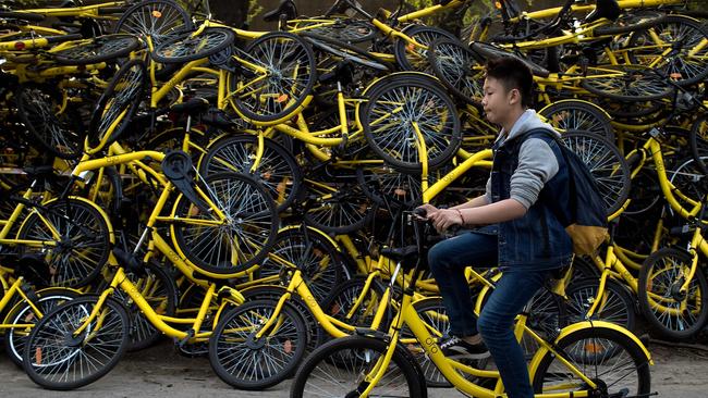 A young man cycles past Ofo shared bicycles at a repair centre in Beijing.