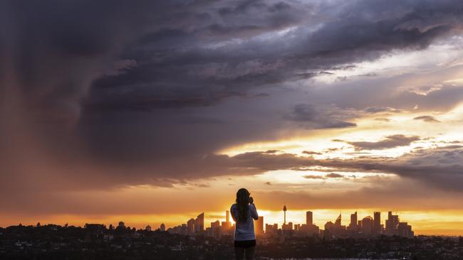 A person looks on as storm clouds roll over Sydney. The Bureau of Meteorology has issued a severe thunderstorm warning for coastal areas of NSW and Queensland on Thursday, with damaging winds, heavy rain and hailstones expected. Picture: Brook Mitchell/Getty Images