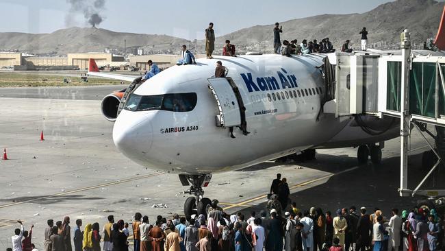 Afghan people climb atop a plane as they wait at the Kabul airport on August 16 after a stunningly swift end to Afghanistan's 20-year war. Picture: AFP