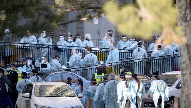 Police and healthcare workers in protective gear prepare to enter one of the locked-down towers at the North Melbourne public housing estate on Wednesday. Picture: NewsWire / Andrew Henshaw