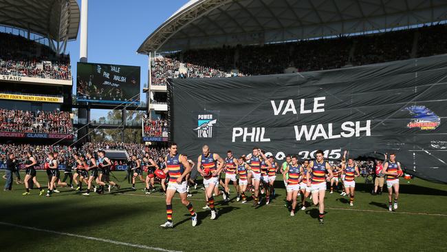 Adelaide and Port Adelaide players run through the same banner before the July 2015 Showdown after Phil Walsh’s death. Picture: AAP/Ben Macmahon