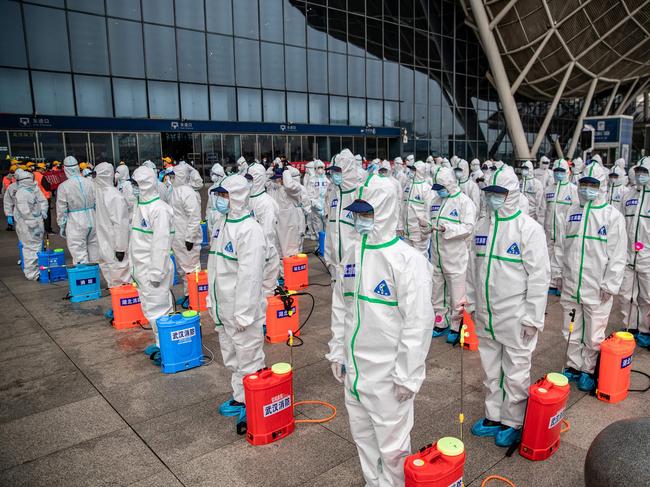 TOPSHOT - Staff members line up at attention as they prepare to spray disinfectant at Wuhan Railway Station in Wuhan in China's central Hubei province on March 24, 2020. - China announced on March 24 that a lockdown would be lifted on more than 50 million people in central Hubei province where the COVID-19 coronavirus first emerged late last year. (Photo by STR / AFP) / China OUT