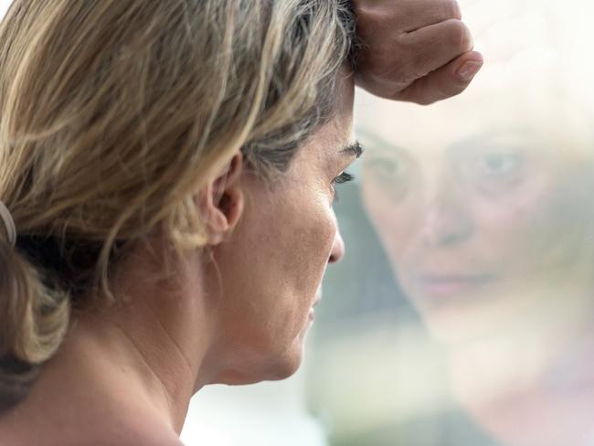 Pensive hispanic mature woman looking through a window. iStock