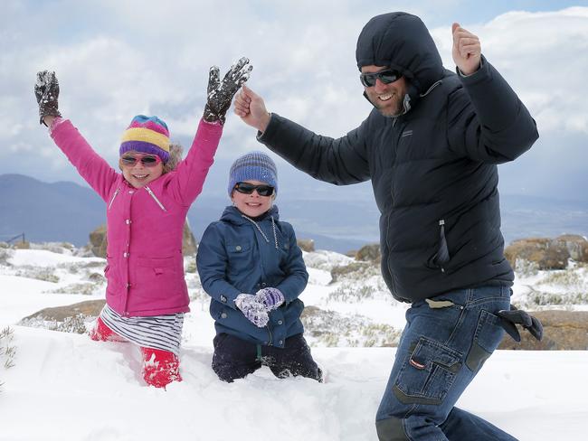 Ben Wells with his children Lucy, 6, and Archer, 4, celebrate reaching Mt Wellington’s snowy summit. Picture: RICHARD JUPE