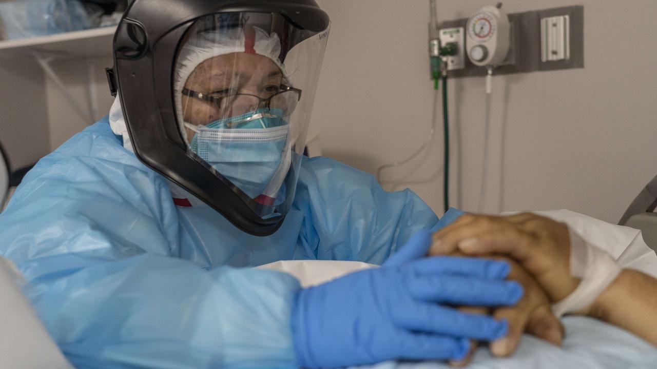 COVID-19 decimated 2020 and the future looks even more bleak. A medical staff member in Texas places her hands on a deceased patient's hands before put the patient into a body bag in the COVID-19 intensive care unit (ICU) Picture: Go Nakamura/Getty Images/AFP.