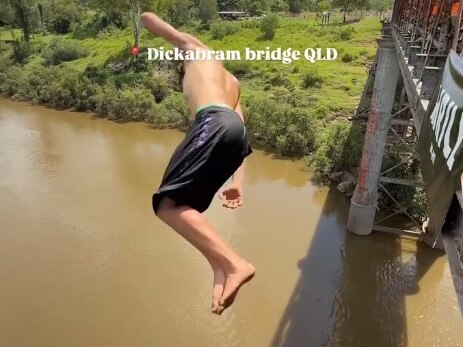 A still from the video of young men doing multiple somersaults  from the top of the arch of Queenslandâs oldest bridge at least 30m above the water has had almost 100,000 views and plenty of criticism.