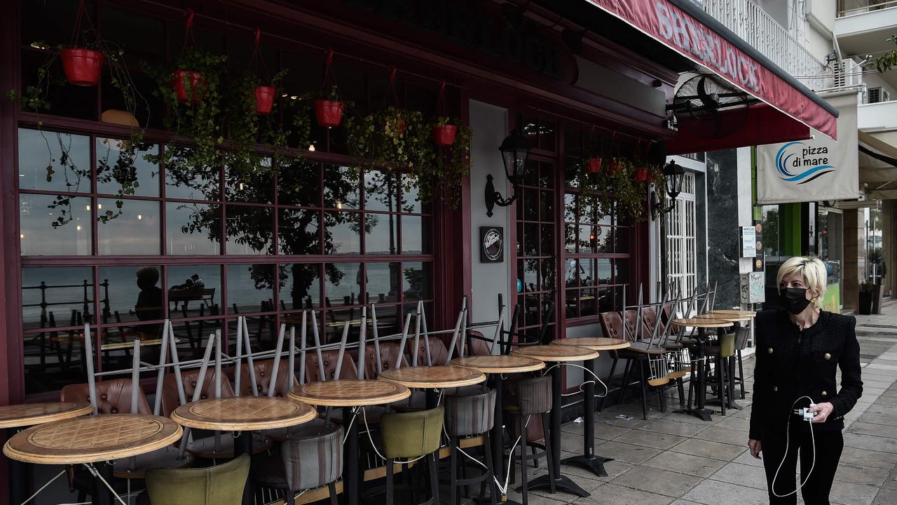 A woman walks past a closed cafe in Thessaloniki on November 16 after restaurant, cafe and bars owners staged a 24-hours strike, protesting Covid-19 related measures and high energy costs. Picture: Sakis MITROLIDIS/AFP