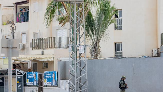 A family looks out from a window at a member of the Israeli security force on patrol on in Sderot. Picture: Getty Images