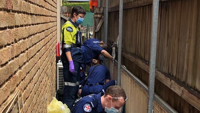 Paramedics treat the man after he landed on concrete between two homes.