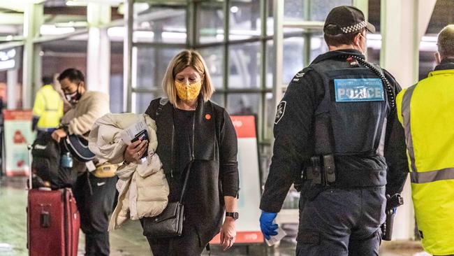 A woman walks past a police officer at Sydney International Airport. Picture: Monique Harmer