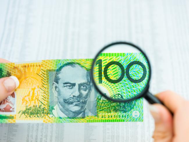 Stock Photo of Australian Money, magnifying glass with $100 note and share market data, tables, investing