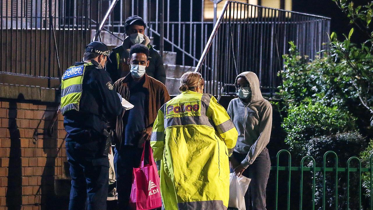 Police talk to residents outside a newly locked-down apartment block in Melbourne. Picture: Ian Currie