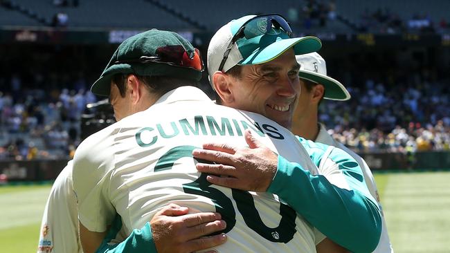 Australia's captain Pat Cummins gives a hug to team's coach Justin Langer (R) after Australia won the match and retained the Ashes at the end of the third Ashes cricket Test match between Australia and England in Melbourne on December 28, 2021. (Photo by Hamish Blair / AFP) / -- IMAGE RESTRICTED TO EDITORIAL USE - STRICTLY NO COMMERCIAL USE --