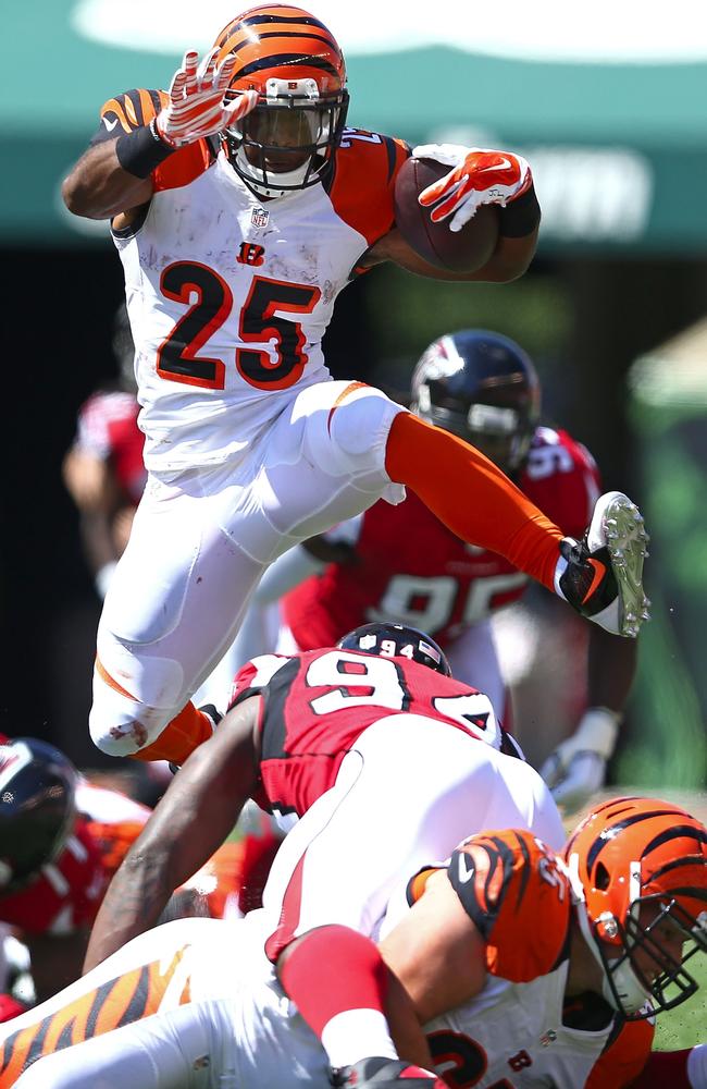 Giovani Bernard #25 of the Cincinnati Bengals jumps over Jonathan Massaquoi #94 of the Atlanta Falcons.