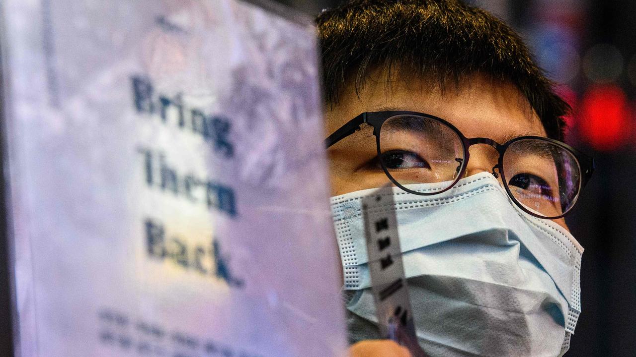 Pro-democracy activist Joshua Wong hold signs in Hong Kong in support of the 12 local activists held in mainland China, after the coast guard intercepted a boat transporting them to Taiwan in late August. Picture: Anthony Wallace/AFP