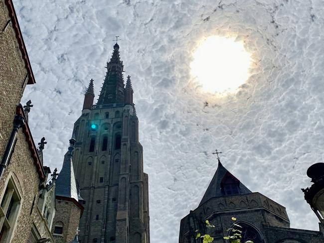 ONE TIME WEB USE ONLY - FEE APPLIES FOR REUSE - A wandering tourist photographed a cloudy sky in Belgium - eerily similar to Vincent van Gogh's famous The Starry Night painting. See SWNS story SWOCsky; Doron Berlin, 31, was on holiday in ancient medieval town Bruges last July when she happened on the incredible sight. Struck by the sky's resemblance to Dutch painter Van Gogh's 19th-century masterpiece, Doron stood transfixed before reaching for her camera.  He captured the sight of swirling clouds of blue and grey set against the brilliant sun and spires near Bruges' Belfry bell tower. The canadian oncologist described the moment as "magical and beautiful". Doron said: "The clouds were particularly striking, and the effect of the sun shining into the camera created a very interesting vortex-type look. "That, mixed with the amazing architecture in Bruges and good lighting all came together for a great oil-on-canvas feel."