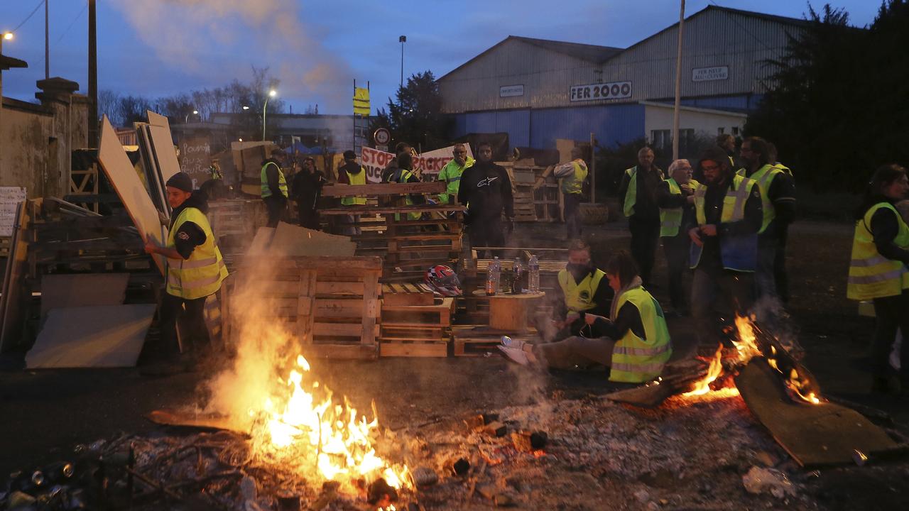 Demonstrators stand in front of a makeshift barricade set up by the so-called yellow jackets to block the entrance of a fuel depot in Le Mans, western France. Picture: AP