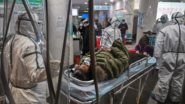 Medical staff wearing protective clothing to help stop the spread of a deadly virus which began in the city, arrive with a patient at the Wuhan Red Cross Hospital.