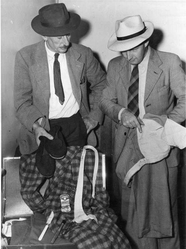 SA police officers Det Sgt Lionel Leane with PCC D. Bartlett examine clothing found in a suitcase at Adelaide Railway Station.