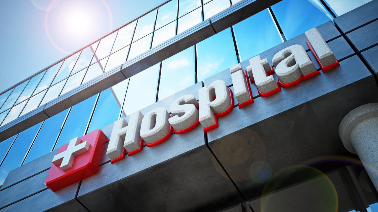 Hospital building exterior and hospital sign. Reflection of blue sky on the windows.