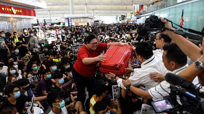 A tourist (C) gives her luggage to security guards as she tries to enter the departures gate during another demonstration by pro-democracy protesters at Hong Kong's international airport on August 13, 2019. - Protesters blocked passengers at departure halls of Hong Kong airport on August 13, a day after a sit-in forced authorities to cancel all flights to and from the major international hub. (Photo by Philip FONG / AFP)