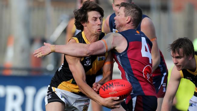 Rhys Magin fires off a handball under pressure from Andrew Collins. Picture: Yuri Kouzmin