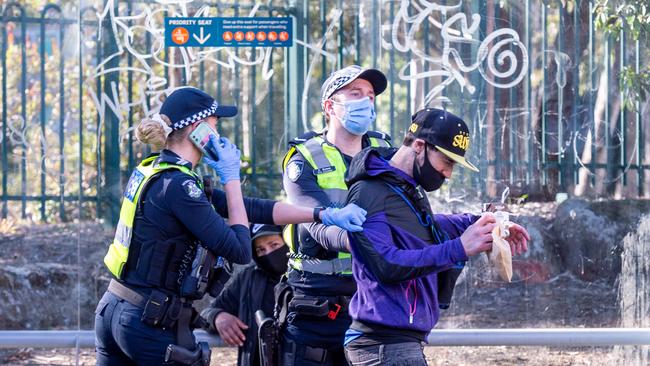 Victoria police question a man at a tram stop on Brunswick Street, Fitzroy. Picture: Jake Nowakowski