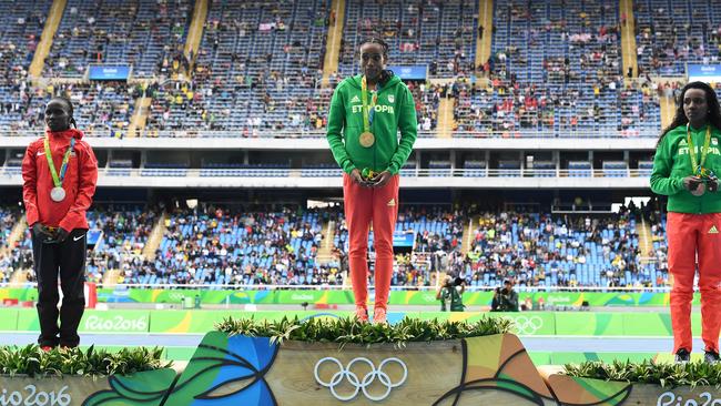 Silver medallist Kenya's Vivian Jepkemoi Cheruiyot (L), Gold medallist Ethiopia's Almaz Ayana (C), and Bronze medallist Ethiopia's Tirunesh Dibaba stand on the podium during the medal ceremony for Women's 10,000m athletics event at the Rio 2016 Olympic Games at the Olympic Stadium in Rio de Janeiro on August 12, 2016. / AFP PHOTO / Jewel SAMAD