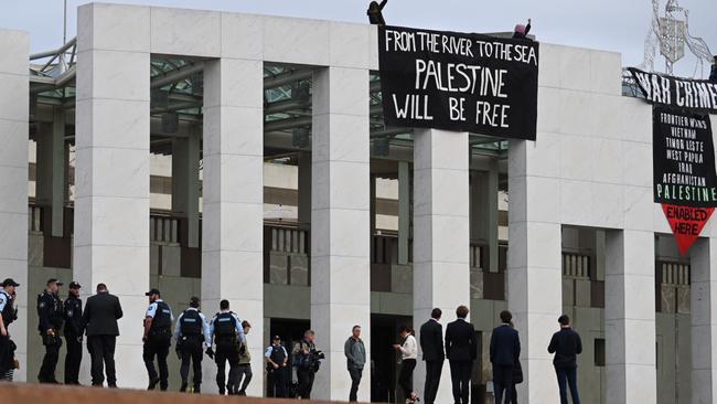 Pro-Palestine protesters have taken to the roof of Parliament House to unfurl banners. Picture: Martin Ollman