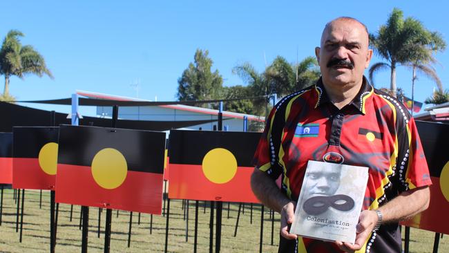 Dr Kerry Blackman with a book he co-authored Colonisation Through Black Eyes.