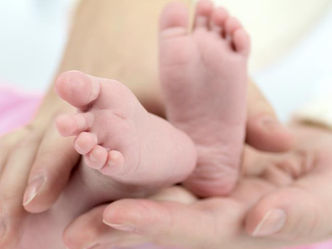 Generic photo illustrating IVF. Mother's hands holding Baby's tiny feet. Picture: iStock