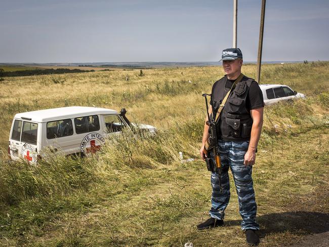 A member of a local militia stands guard as vehicles transporting observers from the Organisation for Security and Co-operation in Europe and International Committee of the Red Cross visit the main crash site of Malaysia Airlines flight MH17 in Grabovo, Ukraine. Picture: Rob Stothard/Getty Images