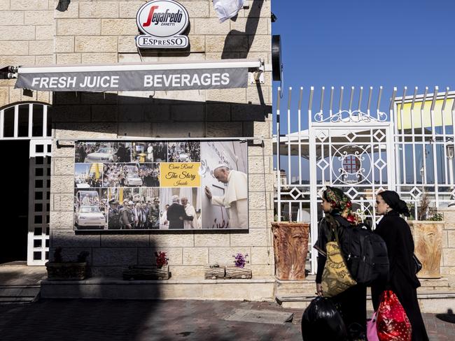 Palestinian women walk past a coffee shop with a pictures of Pope Francis on December 18, 2023 in Bethlehem, West Bank. Picture: Maja Hitij/Getty Images