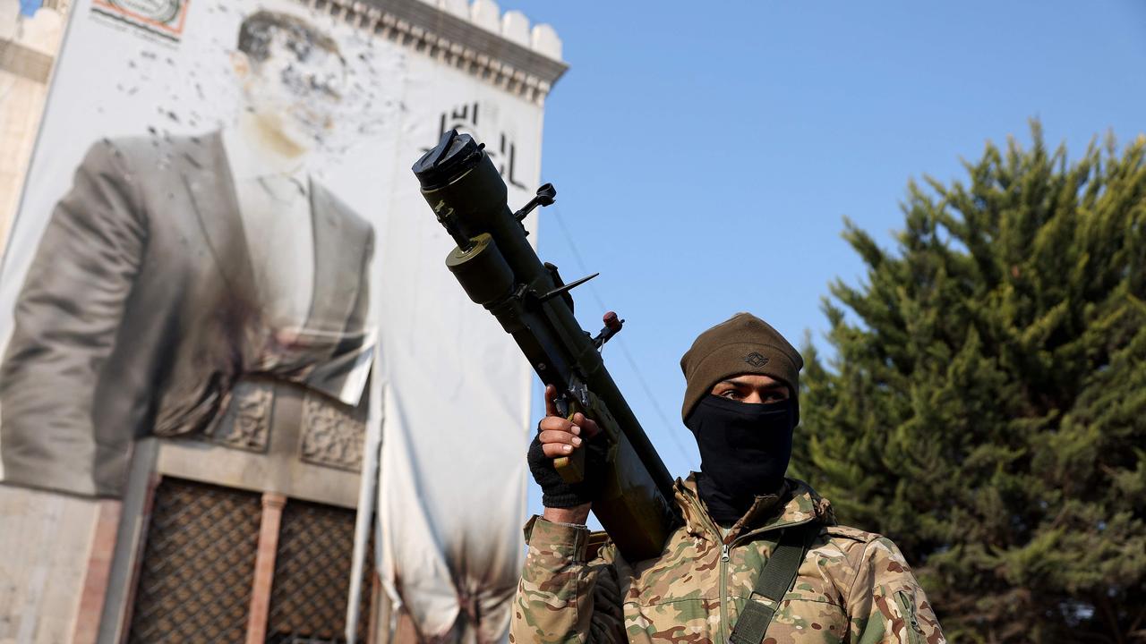 An anti-government fighter holds a weapon as he keeps position near a defaced portrait of Syrian President Bashar al-Assad, in the city of Hama. Picture: Omar Haj Kadour/AFP