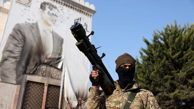 An anti-government fighter holds a weapon as he keeps position near a defaced portrait of Syrian President Bashar al-Assad, in the city of Hama. Picture: Omar Haj Kadour/AFP