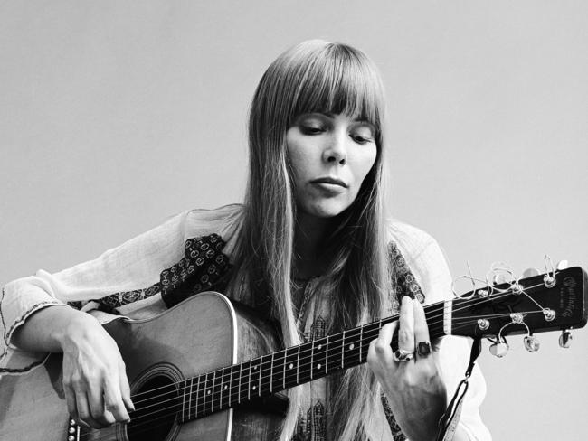 Portrait of Canadian musician Joni Mitchell seated on the floor playing acoustic guitar, November 1968. This image is from a shoot for the fashion magazine Vogue. Mitchell wears a loose-fitting white dress. (Photo by Jack Robinson/Getty Images)