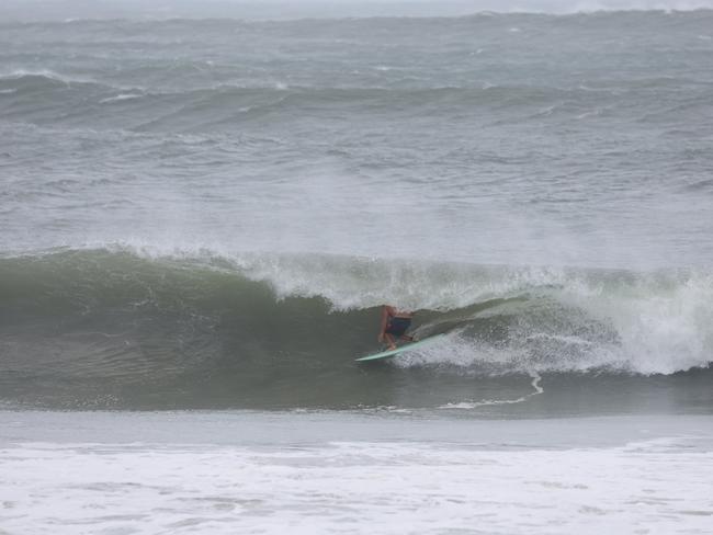 Surfers pictured at Main Beach in Byron Bay as people gather on the beach to watch on. Picture: Rohan Kelly