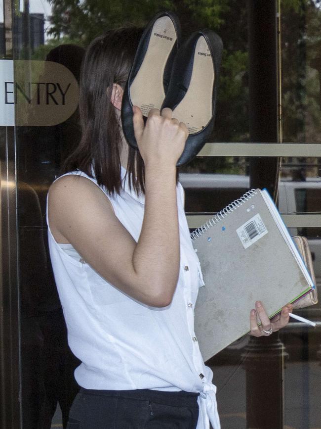 Jessica Glaser holds her shoes to her face as she leaves the District Court.