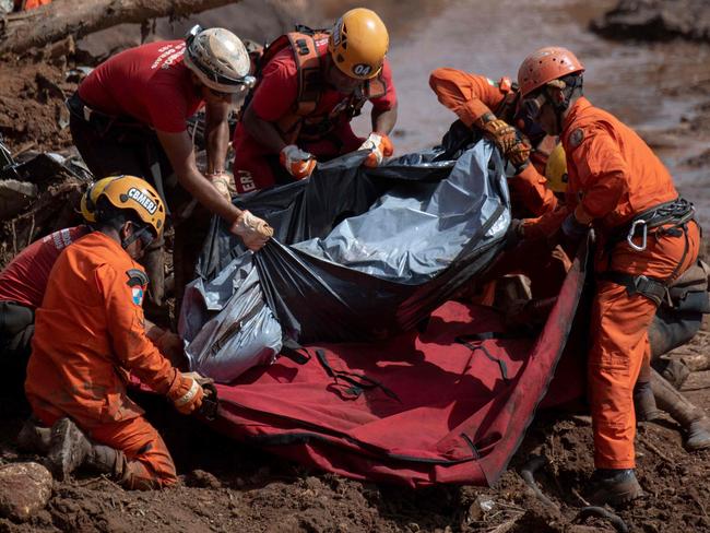 TOPSHOT - Firefighters recover the body of a victim of Friday's dam collapse at an iron-ore mine belonging to Brazil's giant mining company Vale near the town of Brumadinho, state of Minas Gerais, southeastern Brazil, on January 28, 2019. - The search for survivors intensified on Monday, on its fourth day, with the support of an Israeli contingent, after communities were devastated by a dam collapse that killed at least 60 people -- with hopes fading for 292 still missing. A barrier at the site burst on Friday, spewing millions of tons of treacherous sludge and engulfing buildings, vehicles and roads. (Photo by Mauro PIMENTEL / AFP)