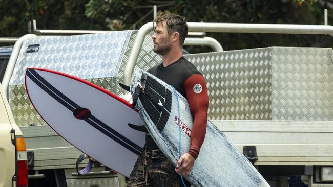 Chris Hemsworth, 39, strolled to the surf wearing a pair of cargo board shorts and long sleeve wetsuit top, carrying an Emery surfboard under each arm. Picture: Media Mode