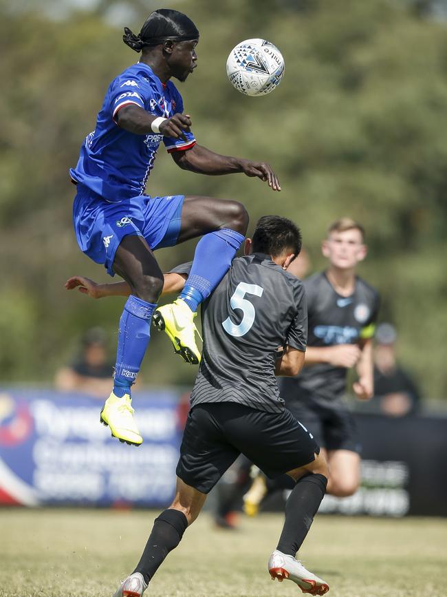 Langwarrin’s John Kuol flies high against Melbourne City’s Mark Karlic. Picture: Valeriu Campan