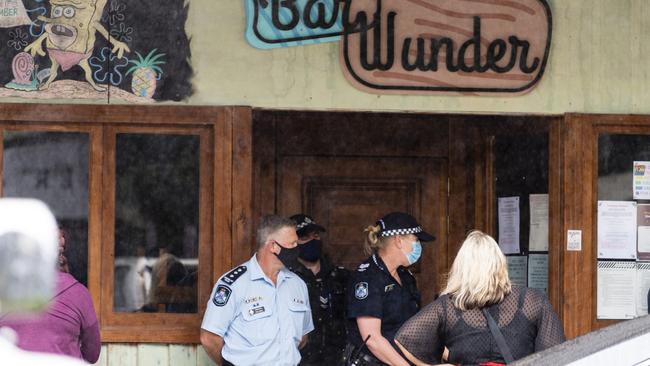 Police stand blocking the entrance to Bar Wunder as people gather on the footpath outside the Toowoomba bar shut down over failing to comply with public health orders. Picture: Kevin Farmer