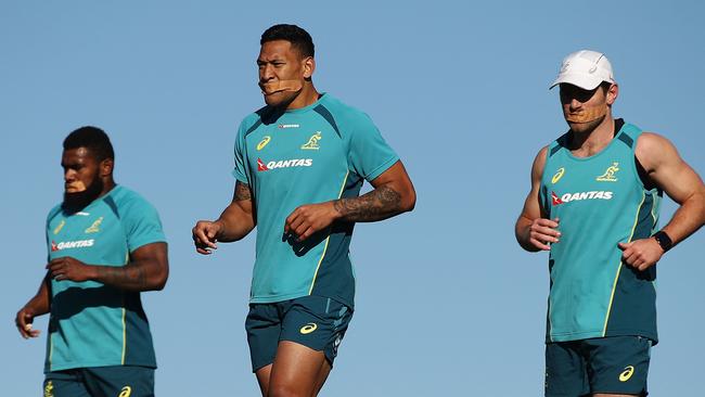 Wallabies players (l-r) Marika Koroibete, Israel Folau and Bernard Foley with their mouths taped shut as they run a hill session at Sydney Park on Saturday.