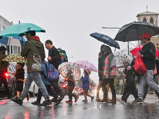 ADELAIDE, AUSTRALIA - NewsWire Photos MAY 30, 2024: Pedestrians cross in Goodwood Rd at Goodwood in the rain. Picture: NCA NewsWire / Brenton Edwards