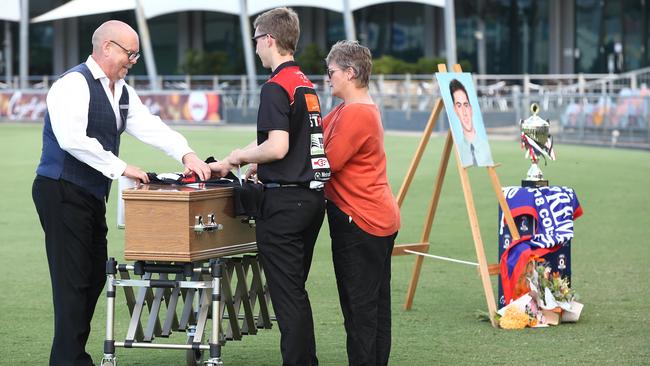 Stephen Oldham, teammate Toby Burkett and mother Mandy Kearsley place a Cairns Saints singlet and a bouquet of flowers onto the casket of Joseph "Joey" Kearsley, who passed away last week after a long fight with cancer. The funeral service at Cazalys Stadium was attended by hundreds of mourners. Picture: Brendan Radke