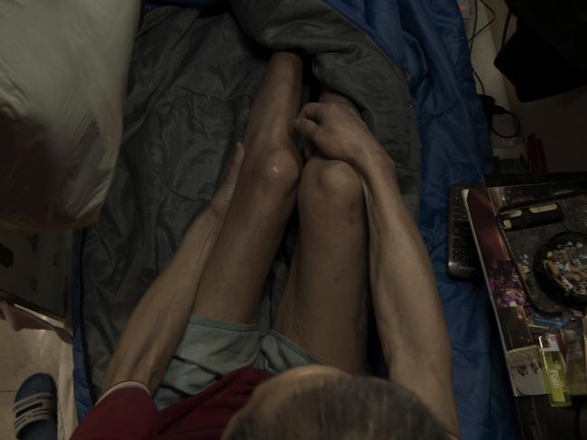 Wong Tat-ming, 63, sits in his space which is crammed with all his meagre possessions, including a sleeping bag, small colour TV and electric fan. He and another elderly resident complain to a visiting social worker about bedbugs and cockroaches. Picture: AP Photo/Kin Cheung