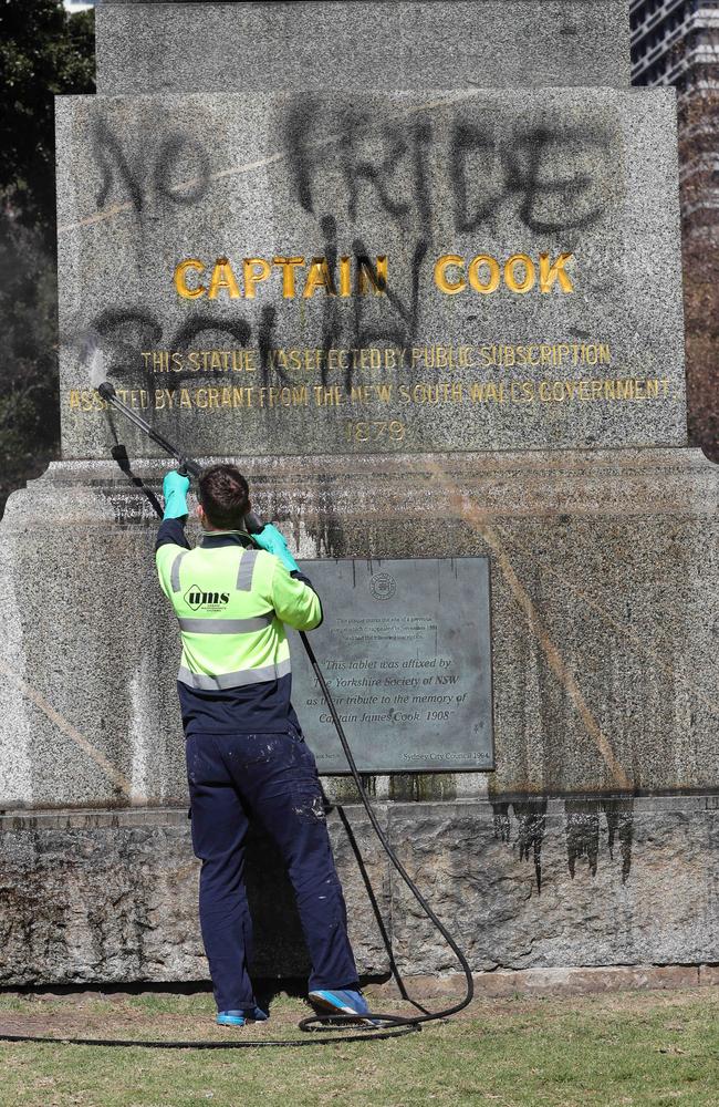 Council workers remove spray paint graffiti from the base of a Captain Cook in Sydney’s Hyde Park.