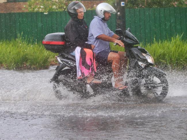 A pair riding a motorbike make their way through heavy flooding on the corner of St Kilda and Grosvenor streets in Brighton. Picture: Hamish Blair