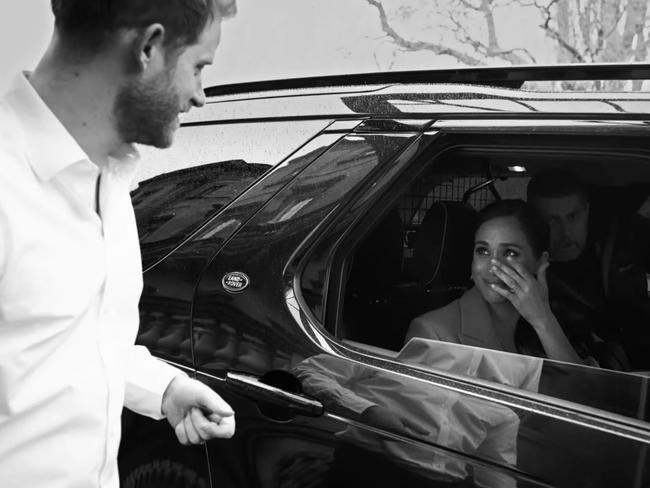 Meghan Markle wipes away a tear while being driven away in an undated image. She appears to be wearing an engagement and wedding ring. Picture: Netflix